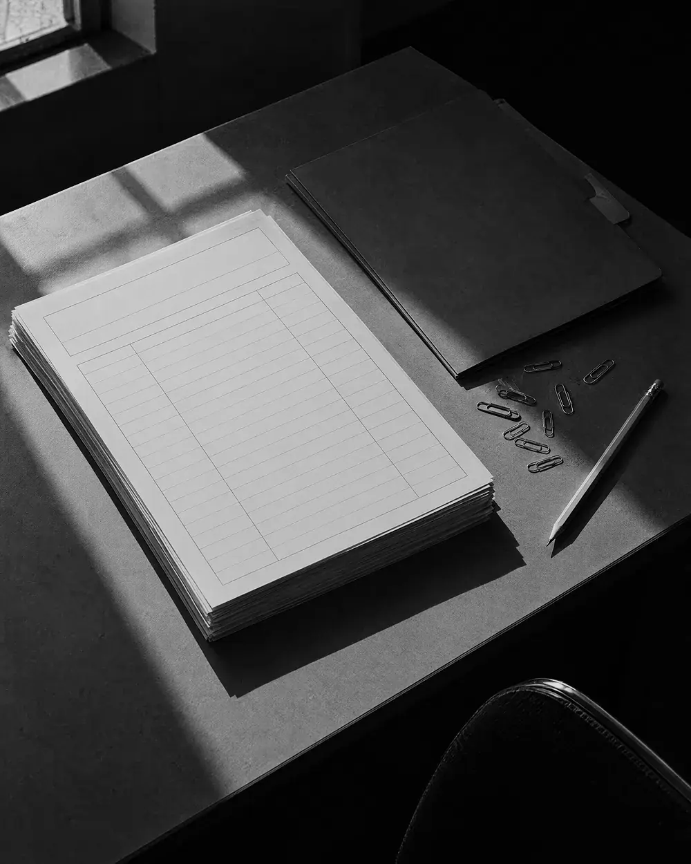Vorbereitete leere Formulare und eine Mappe mit Büroklammern und Bleistift auf einem Tisch, schräg von oben aufgenommen
