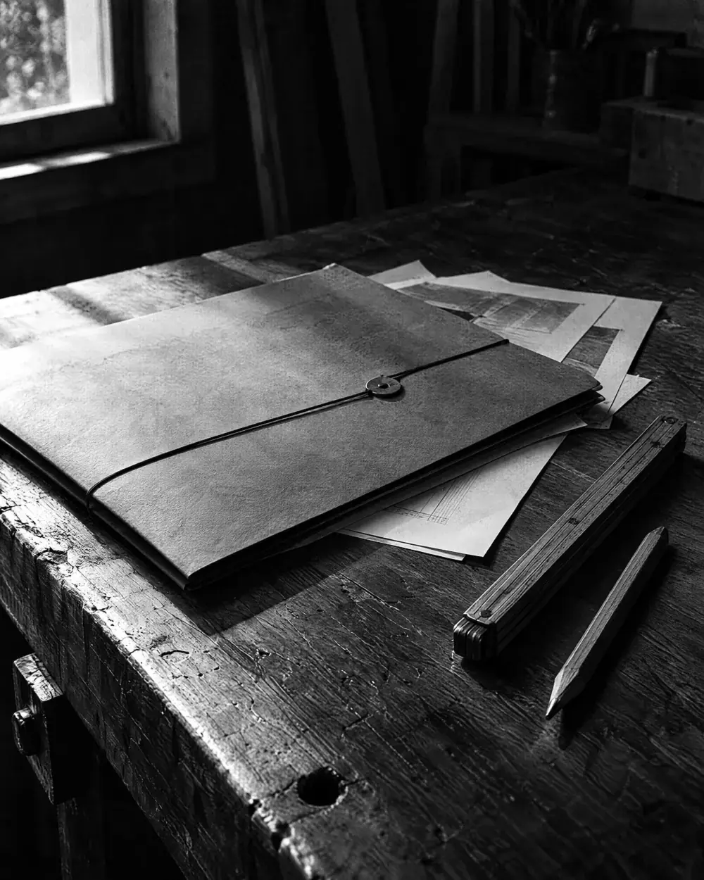 Angebotsmappe mit losen Blättern, Zollstock und Bleistift auf einem Werktisch